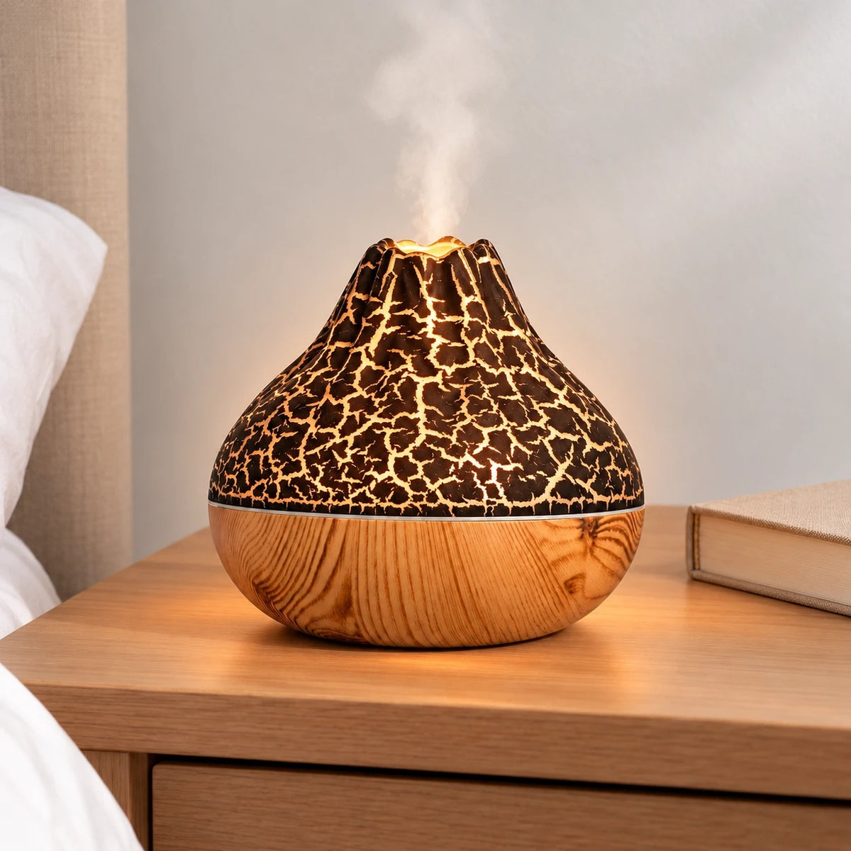 Humidificador volcán negro encendido, con luz cálida y vapor, sobre una mesita de noche