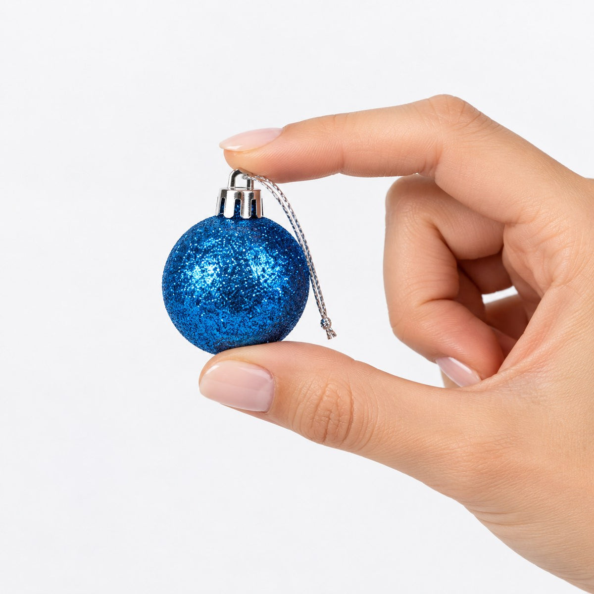 Adorno navideño azul brillante en mano